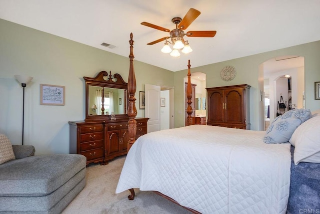 bedroom with light carpet, visible vents, arched walkways, and ceiling fan