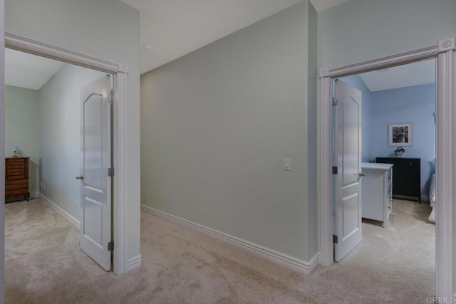 hallway with light colored carpet and baseboards