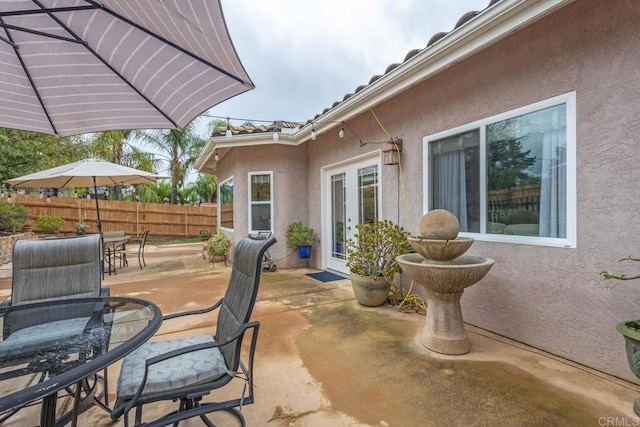 view of patio featuring french doors, outdoor dining area, and fence