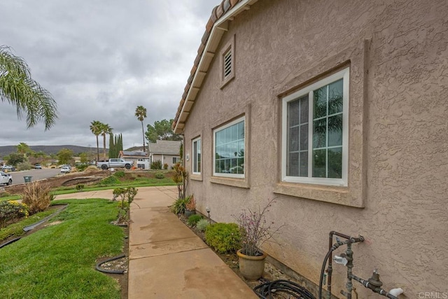 view of side of property with stucco siding and a yard