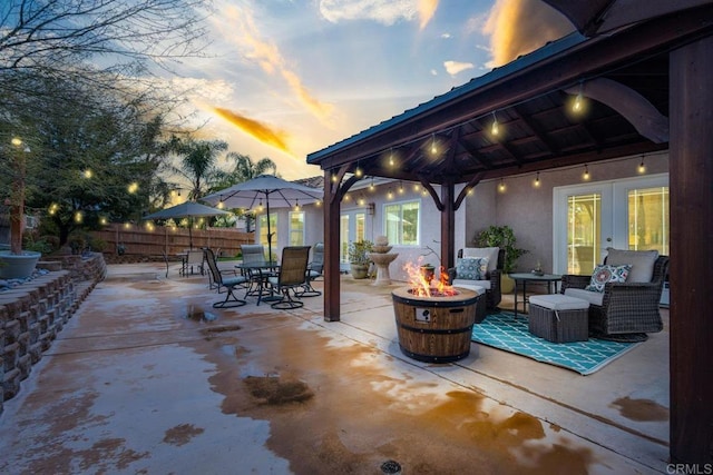 view of patio with an outdoor living space with a fire pit, fence, a gazebo, french doors, and outdoor dining space