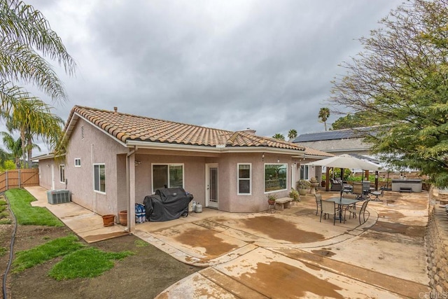 rear view of house with central AC unit, fence, stucco siding, a tile roof, and a patio area