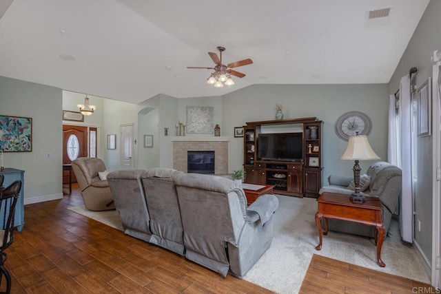 living room with a ceiling fan, wood finished floors, baseboards, a brick fireplace, and vaulted ceiling