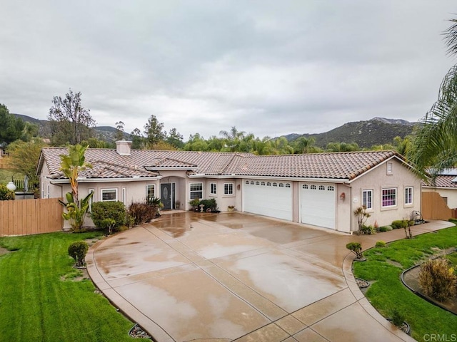 view of front of property featuring fence, a tiled roof, stucco siding, driveway, and an attached garage