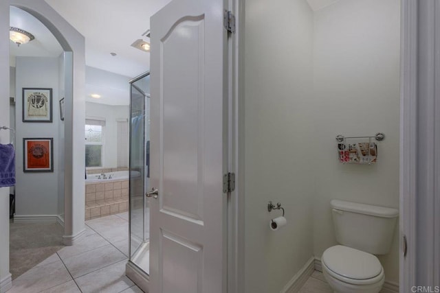 full bath with tiled bath, baseboards, toilet, a shower with shower door, and tile patterned floors