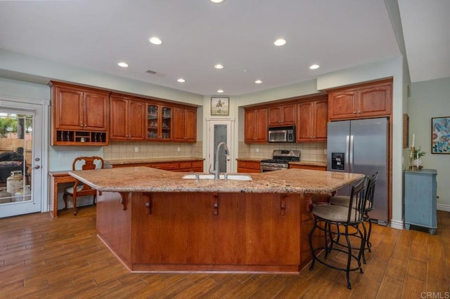 kitchen featuring dark wood-style floors, stainless steel appliances, light stone counters, and a sink