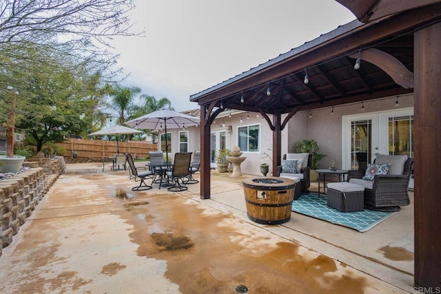 view of patio / terrace featuring fence, an outdoor fire pit, a gazebo, french doors, and outdoor dining space