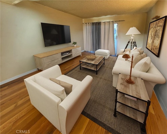 living room featuring a textured ceiling, baseboards, and wood finished floors