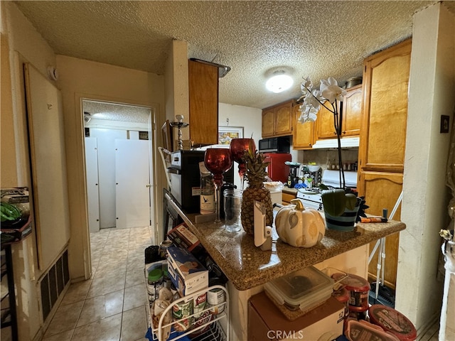 18620 Hatteras St Unit 166, Tarzana, CA 91356 - kitchen with black microwave, brown cabinetry, a textured ceiling, and white gas range oven
