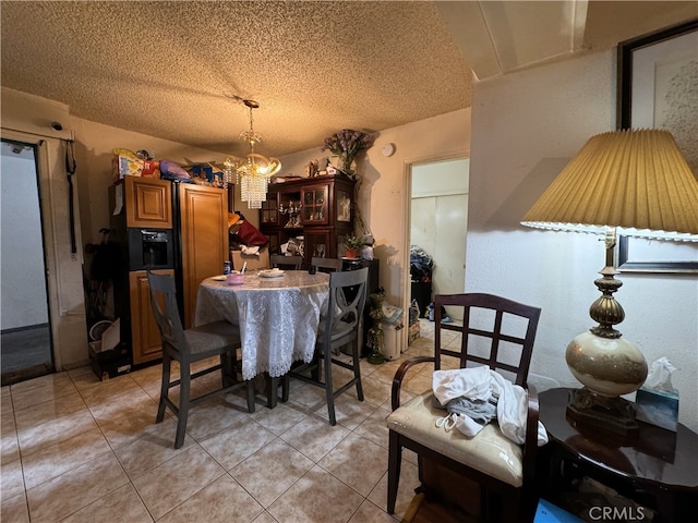 dining area with an inviting chandelier, light tile patterned floors, and a textured ceiling