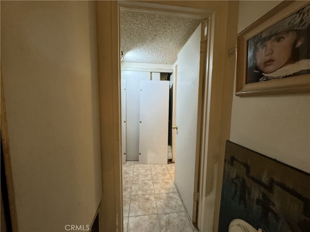 corridor with light tile patterned floors and a textured ceiling