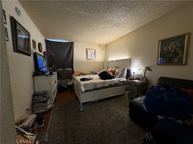 bedroom with a textured ceiling and wood finished floors