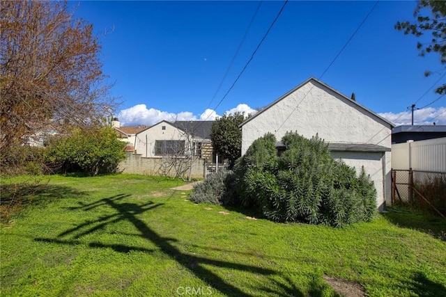 exterior space with stucco siding, a yard, and fence