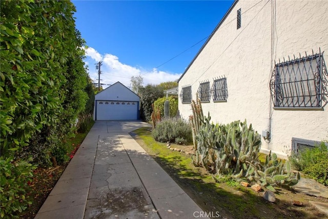 view of side of property featuring an outdoor structure, a garage, and stucco siding