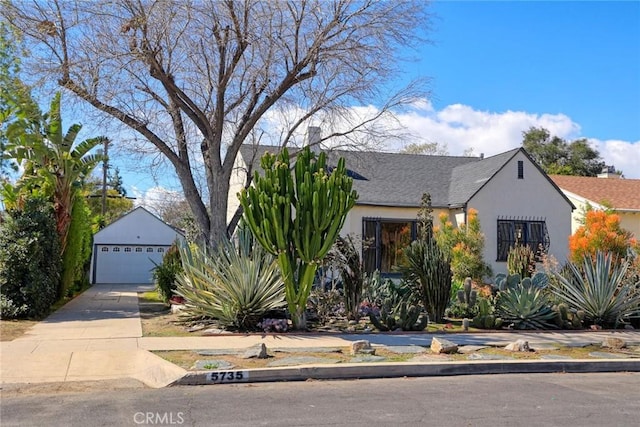 view of front of house with stucco siding, a garage, and an outdoor structure