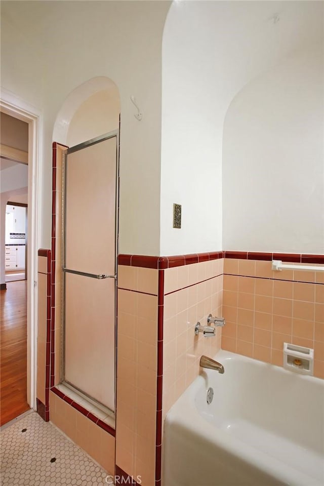 full bath featuring a bath, tile patterned flooring, and tile walls