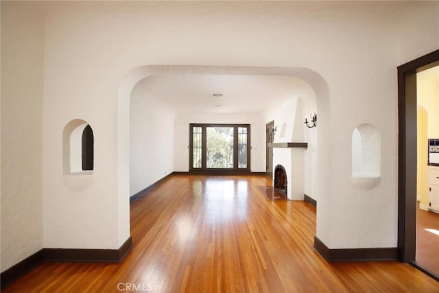 interior space featuring a fireplace with flush hearth, wood finished floors, and baseboards