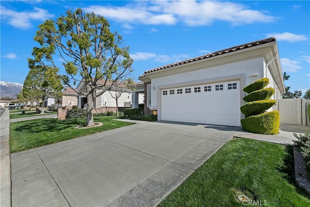 mediterranean / spanish home featuring concrete driveway, a tiled roof, a garage, and stucco siding