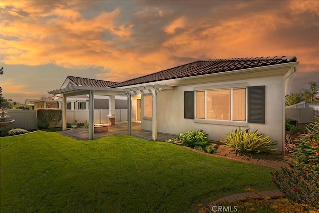 rear view of property with fence, a tile roof, a yard, a patio area, and a pergola