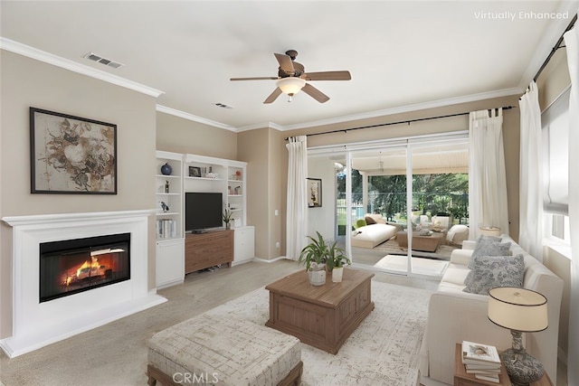 living room with a glass covered fireplace, ceiling fan, visible vents, and ornamental molding