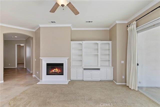 unfurnished living room with visible vents, arched walkways, light colored carpet, and ornamental molding