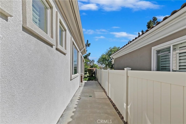 view of side of home with stucco siding and fence