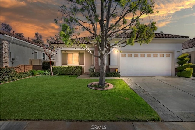 mediterranean / spanish-style home with a front yard, an attached garage, stucco siding, concrete driveway, and a tiled roof