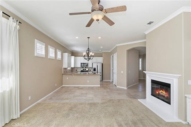 unfurnished living room featuring baseboards, arched walkways, ornamental molding, light carpet, and a glass covered fireplace