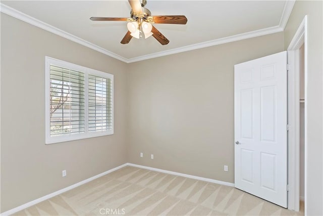 empty room with baseboards, light colored carpet, and crown molding