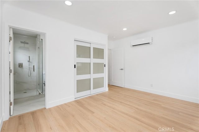 empty room with recessed lighting, baseboards, an AC wall unit, and light wood finished floors