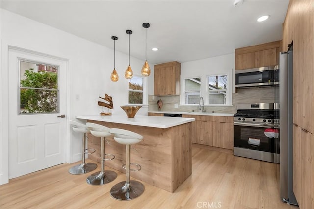 kitchen featuring a wealth of natural light, appliances with stainless steel finishes, a kitchen breakfast bar, and a sink