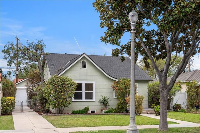 view of front of house with fence, roof with shingles, a front lawn, and a gate