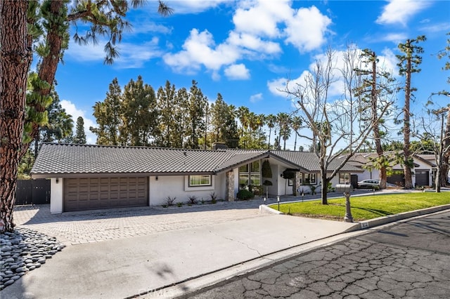 view of front of property featuring a chimney, stucco siding, a garage, a tile roof, and decorative driveway