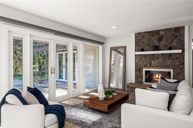 living area with a stone fireplace, wood finished floors, and french doors