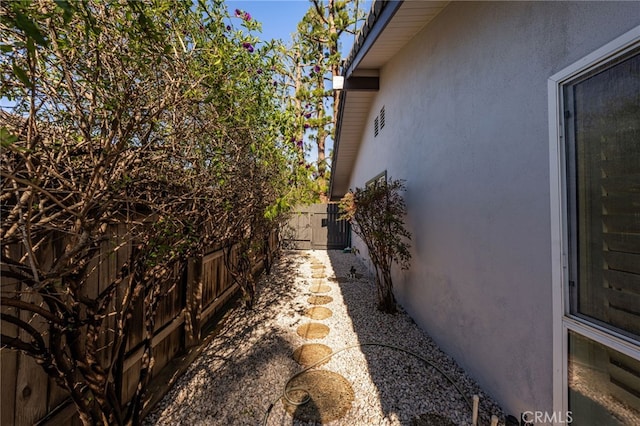 view of side of home featuring stucco siding and fence