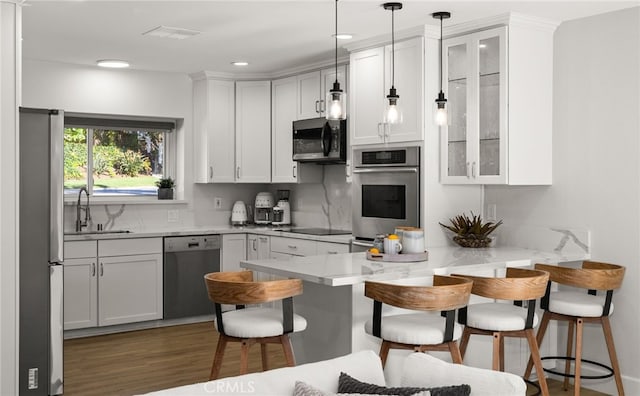 kitchen with decorative light fixtures, a breakfast bar area, appliances with stainless steel finishes, a peninsula, and white cabinets