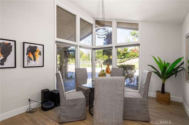 dining space featuring vaulted ceiling, wood finished floors, and baseboards