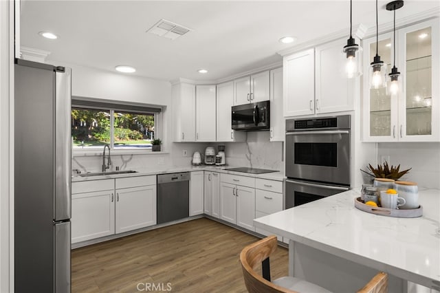 kitchen with visible vents, appliances with stainless steel finishes, wood finished floors, white cabinetry, and a sink