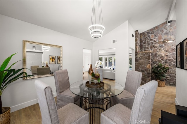 dining room with visible vents, high vaulted ceiling, wood finished floors, baseboards, and a chandelier