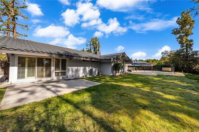 back of property with central air condition unit, a patio, a lawn, and stucco siding