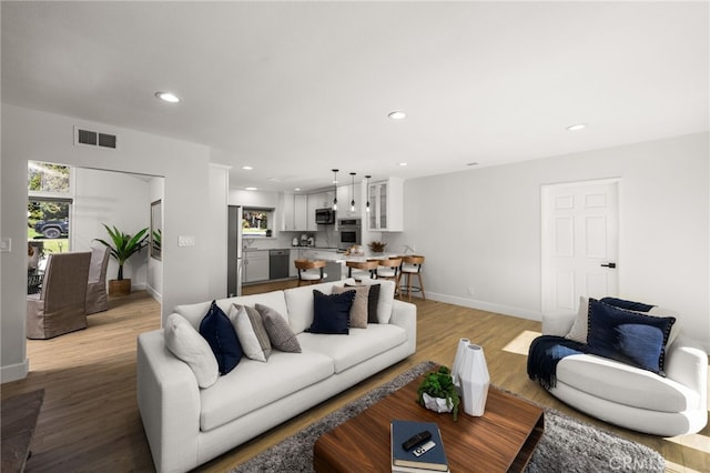 living area featuring light wood-style flooring, recessed lighting, and visible vents