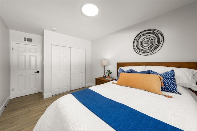 bedroom featuring visible vents, baseboards, a closet, and wood finished floors