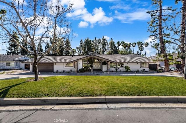 view of front of house with a front yard, driveway, stucco siding, a garage, and a tiled roof