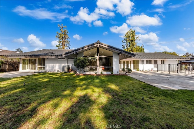 view of front facade featuring a front lawn, a patio, fence, central AC unit, and a tiled roof