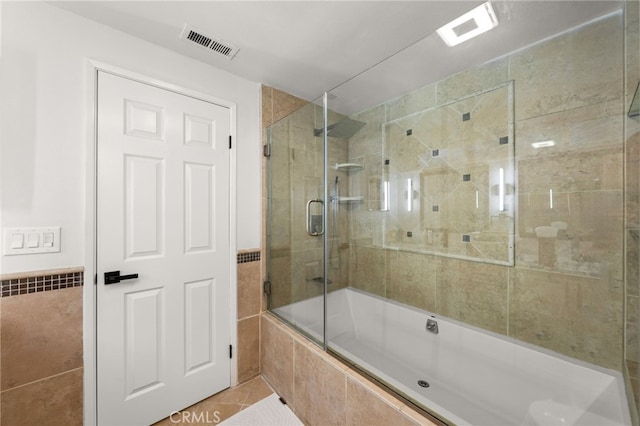 full bathroom featuring tile patterned flooring, tile walls, visible vents, and tiled shower / bath combo