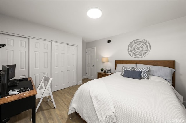 bedroom with light wood-type flooring, visible vents, and a closet