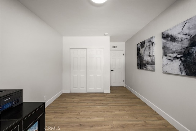 bedroom with a closet, visible vents, light wood-style flooring, and baseboards