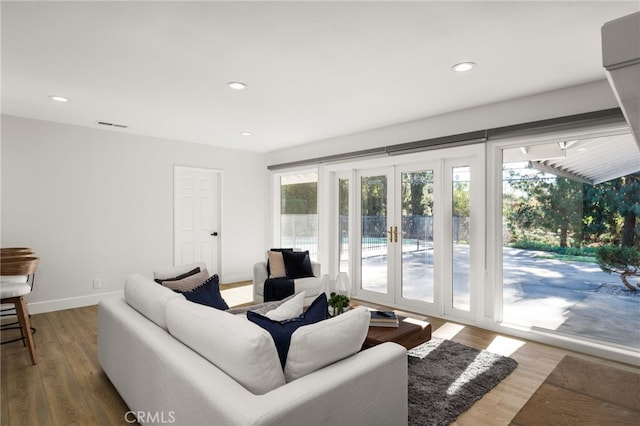 living area featuring visible vents, baseboards, recessed lighting, french doors, and wood finished floors