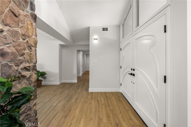 hallway with visible vents, baseboards, and light wood-style floors