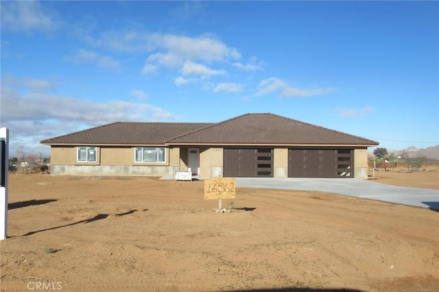 view of front facade featuring a garage, concrete driveway, stucco siding, and a tile roof